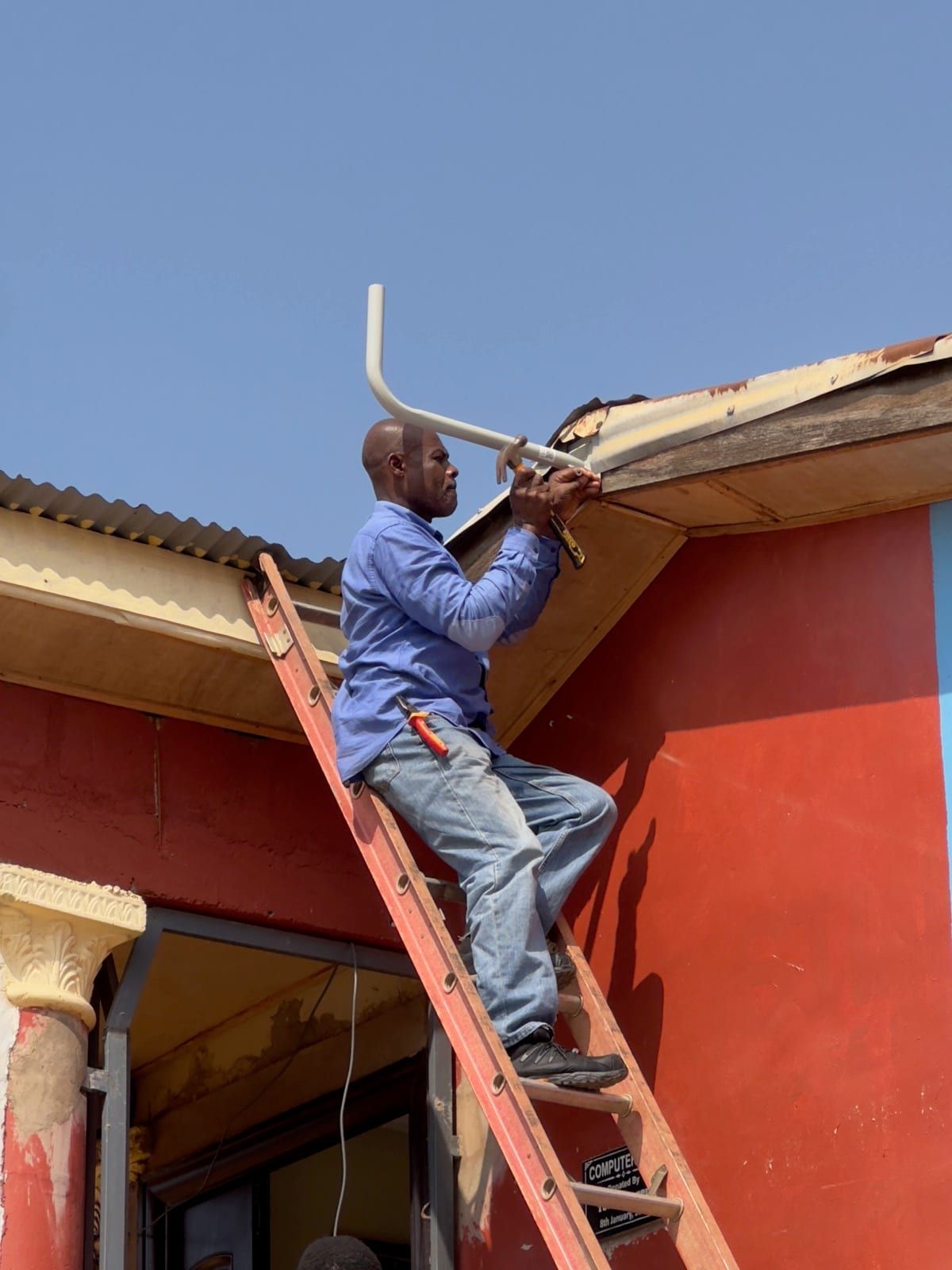 Techniker installiert Starlink-Antenne auf dem Schuldach in Kumasi